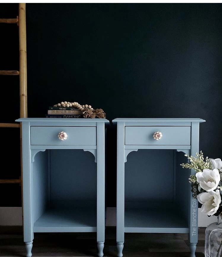 Blue painted matching nightstands against a black wall